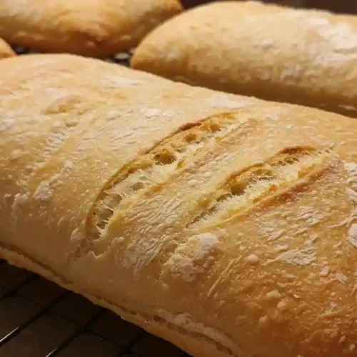 Pain ciabatta maison doré et croustillant sur une grille de refroidissement.